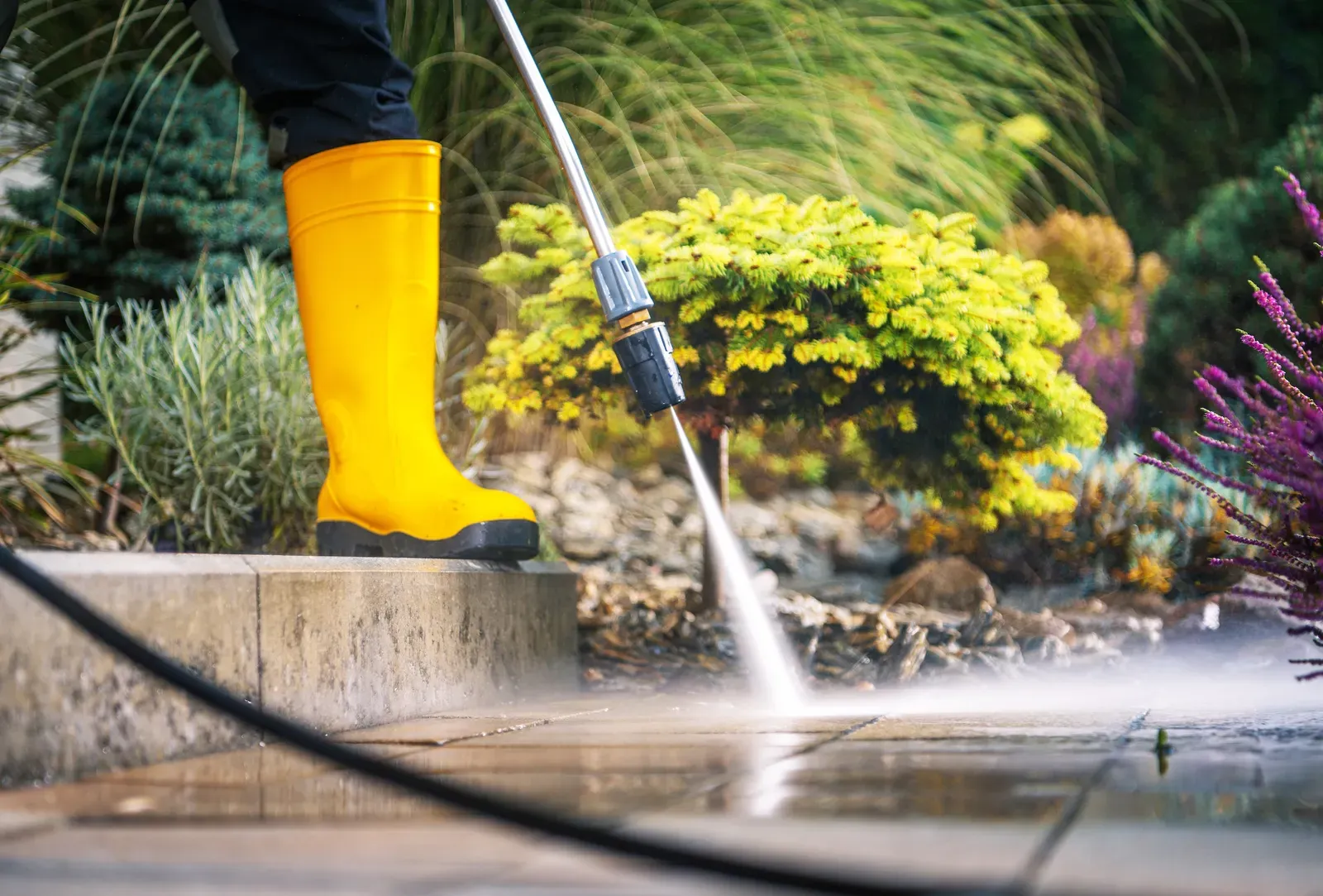 Close-up of a pressure washer cleaning paver stones on a garden walkway