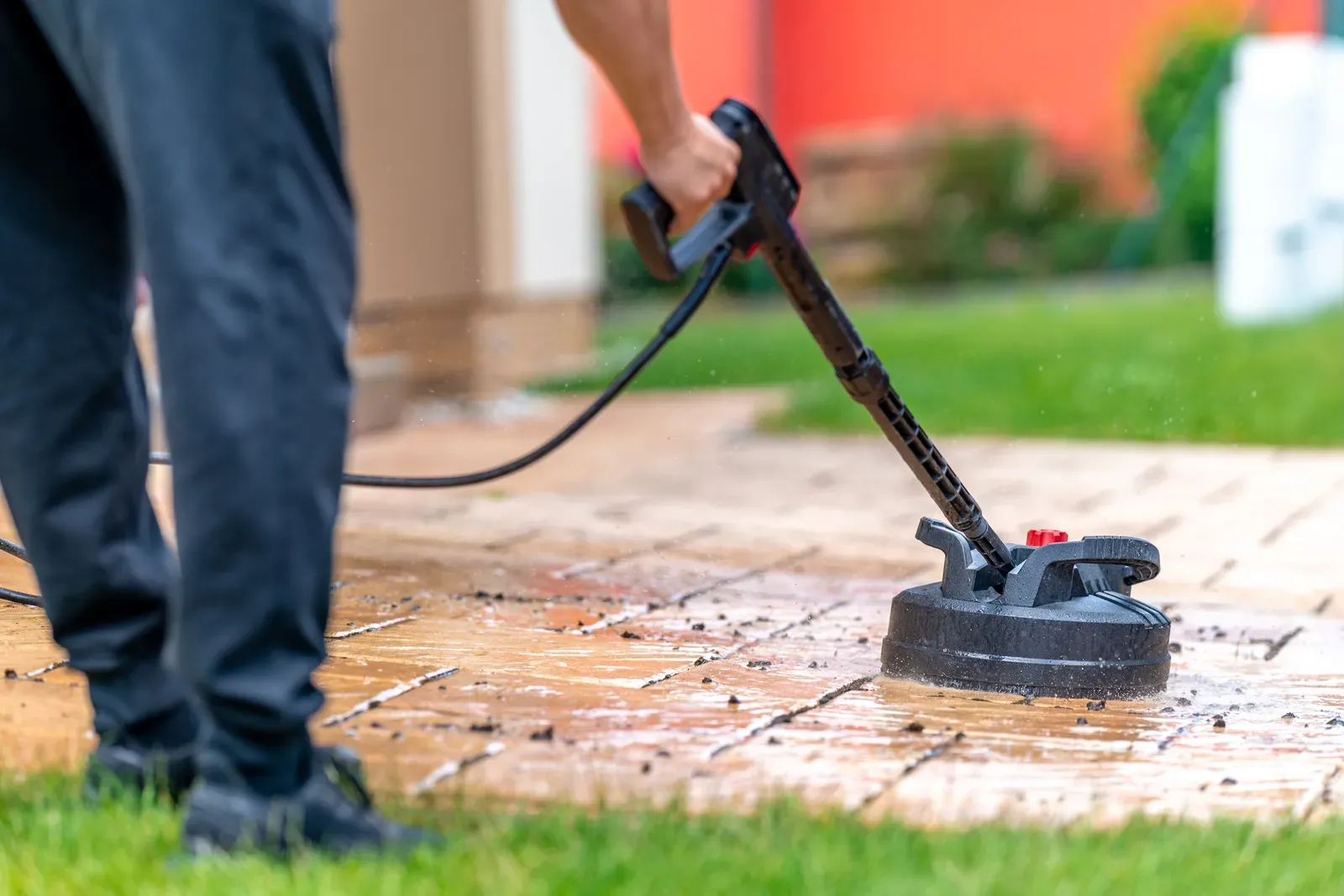 Surface cleaner lifting built-up grime from patio pavers, leaving a bright, clean stripe
